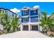 Beautiful two-story blue home featuring a gravel driveway, landscaping, and a two-car garage at 201 Bay N Dr, Bradenton Beach, FL 34217