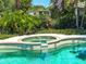 Swimming pool with in-ground hot tub surrounded by lush tropical landscaping at 214 49Th W St, Bradenton, FL 34209