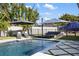Relaxing backyard with sparkling pool, stylish outdoor seating, and mature tropical landscaping at 2202 Alpine Ave, Sarasota, FL 34239
