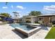 A serene backyard features a pool, spa, outdoor kitchen, manicured lawn, and elegant travertine stone patio at 2202 Alpine Ave, Sarasota, FL 34239