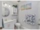 Well-lit bathroom with a round mirror, white cabinets, and coastal-themed art and towels at 308 Timber Lake Dr, Bradenton, FL 34210
