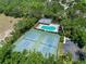 Aerial view of community pool, tennis courts, and parking area surrounded by mature trees at 3108 River Woods Dr, Parrish, FL 34219