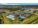Aerial view showcasing community amenities, featuring a pool, clubhouse, tennis courts, and playground, plus nearby lake and homes at 3375 Juniper Springs St, Wesley Chapel, FL 33543