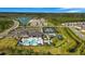 Aerial view of the community amenities including a pool, clubhouse, tennis courts, and playgrounds, set amongst homes and a lake at 3375 Juniper Springs St, Wesley Chapel, FL 33543