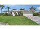 Well-maintained single-story home featuring a lush green lawn, a two-car garage, and tropical landscaping at 3572 Ferndell, Sarasota, FL 34235