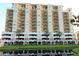 Beautiful multi-story condo building with balconies, palm trees, and pond reflections at 501 Haben Blvd # 704, Palmetto, FL 34221