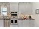 Gray kitchen cabinets and stainless appliances, accented by granite counters and mosaic tile backsplash at 5437 Manchini St, Sarasota, FL 34238
