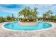 A circular pool with a central island of palm trees and a clear blue sky at 5437 Manchini St, Sarasota, FL 34238
