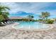 Resort-style pool featuring sun loungers, palm trees, and a splash pad under a blue sky at 5437 Manchini St, Sarasota, FL 34238