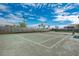 Well-maintained tennis court with clear markings, surrounded by lush landscaping and tall palm trees under a sunny sky at 5437 Manchini St, Sarasota, FL 34238