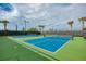 Vibrant blue tennis courts surrounded by lush greenery and palm trees under a sunny sky, perfect for recreational play at 5437 Manchini St, Sarasota, FL 34238