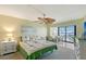 Bright bedroom boasts neutral paint, palm-themed bedding, a ceiling fan, and a private screened balcony at 5855 Midnight Pass Rd # 512, Sarasota, FL 34242