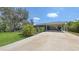 Charming home exterior featuring a well-manicured lawn, mature trees, and a covered carport for convenient parking at 6365 Jim Davis Rd, Parrish, FL 34219