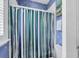 Charming bathroom with blue floral wallpaper, striped shower curtain, and decorative artwork at 7011 Portmarnock Pl, Lakewood Ranch, FL 34202