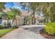 Elegant beige stucco home features a tile roof, arched windows, and a three-car garage at 7011 Portmarnock Pl, Lakewood Ranch, FL 34202