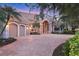 Elegant home featuring a brick driveway, three-car garage, and beautiful landscaping at 7011 Portmarnock Pl, Lakewood Ranch, FL 34202
