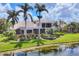 A beautiful two-story home with a screened-in pool, lush landscaping, and palm trees by the water at 7011 Portmarnock Pl, Lakewood Ranch, FL 34202