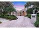 Elegant beige home with a tile roof, arched entryway, circular driveway, and lush landscaping at 7011 Portmarnock Pl, Lakewood Ranch, FL 34202