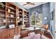 Inviting home office with custom wood bookshelves, a classic desk, and a view of the landscaped yard at 7011 Portmarnock Pl, Lakewood Ranch, FL 34202