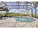 A beautiful screened-in pool and spa area featuring an outdoor kitchen and lush landscaping at 7011 Portmarnock Pl, Lakewood Ranch, FL 34202