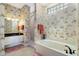 A well-lit bathroom features a tub, glass block window, vanity with granite countertop, and floral wallpaper at 8715 52Nd E Ave, Bradenton, FL 34211
