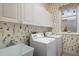 Functional laundry room with white cabinets, utility sink, washer, dryer, and charming wallpaper at 8715 52Nd E Ave, Bradenton, FL 34211