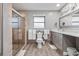 Bright bathroom featuring tile shower, grey cabinets, and an elongated toilet at 9080 Caloosa Dr, Venice, FL 34293