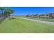 Backyard featuring a lush green lawn, palm trees, a walking path, and scenic water views at 10411 Winding Stream Way, Bradenton, FL 34212