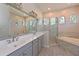 Bathroom with double sinks, shower, bathtub, tile floors, and unique arched windows at 10411 Winding Stream Way, Bradenton, FL 34212