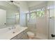 Bathroom featuring gray cabinets, a double vanity, a walk-in shower with glass doors, and a window at 10411 Winding Stream Way, Bradenton, FL 34212