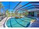 Screened-in pool with rock waterfall and landscaping, surrounded by palm trees at 10411 Winding Stream Way, Bradenton, FL 34212