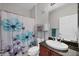 Cozy bathroom featuring vanity with dark granite countertop and floral shower curtain at 10720 Lemon Creek Loop # 103, Englewood, FL 34224