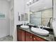 Elegant bathroom featuring double sinks, granite countertop, stylish mirrors, and tiled shower at 10720 Lemon Creek Loop # 103, Englewood, FL 34224
