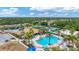 Aerial view of a large community pool featuring a sundeck, umbrellas, tropical landscaping, and tennis courts at 11702 Anhinga Avenue, Venice, FL 34292