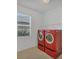Well-lit laundry room featuring modern red washer and dryer units and a window at 14265 17Th E Ct, Parrish, FL 34219