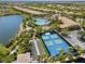 Aerial view of the community's pool, clubhouse, tennis, basketball, and bocce ball courts next to a lake at 1520 Dorgali Dr, Sarasota, FL 34238