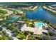 Aerial view of the community pool, clubhouse, and tennis courts along a lake at 1520 Dorgali Dr, Sarasota, FL 34238