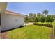 Green side yard featuring lush grass, trimmed hedges, and mature trees creating a serene outdoor space at 1520 Dorgali Dr, Sarasota, FL 34238
