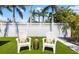 Charming backyard with lush green lawn, white Adirondack chairs, tropical foliage, and decorative white gravel at 1724 Cheyenne St, Sarasota, FL 34231