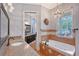 Well-lit bathroom featuring a soaking tub, chandelier, granite countertops, and mirrored closet doors at 1788 Palm View Rd, Sarasota, FL 34240