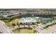 Aerial view of the community featuring a clubhouse, pool, tennis courts, and lush landscaping around a tranquil lake at 18525 Midsummer Pl, Venice, FL 34293