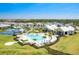 Stunning aerial view of a modern community featuring a pool, clubhouse, tennis courts, and scenic landscaping at 18525 Midsummer Pl, Venice, FL 34293