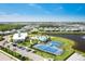 Breathtaking aerial view showcasing a community pool, clubhouse, tennis courts, and beautiful lake at 18525 Midsummer Pl, Venice, FL 34293
