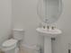 Modern half-bath with pedestal sink, decorative mirror and neutral color palette offers a clean aesthetic at 18525 Midsummer Pl, Venice, FL 34293
