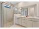 Contemporary bathroom with dual vanity sinks, large mirror, glass-enclosed shower, and tiled walls at 18525 Midsummer Pl, Venice, FL 34293