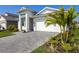 Front exterior view showcasing lush landscaping, a paved driveway, and a white garage door at 18525 Midsummer Pl, Venice, FL 34293