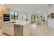 Open concept kitchen with an island that flows into the living room with large windows at 18525 Midsummer Pl, Venice, FL 34293