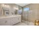 Bright bathroom with dual vanities, a tiled shower with glass enclosure, and modern fixtures at 1907 Woodleaf Hammock Ct, Bradenton, FL 34211