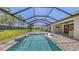 Screened outdoor pool with waterfall feature, sun loungers, brick paver patio, and lush backyard at 1907 Woodleaf Hammock Ct, Bradenton, FL 34211