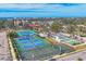Expansive aerial view showcasing community tennis courts, pickle ball courts, and a parking area near the coast at 210 Santa Maria St # 244, Venice, FL 34285